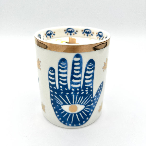 Ceramic candle holder with blue hand design on a white background