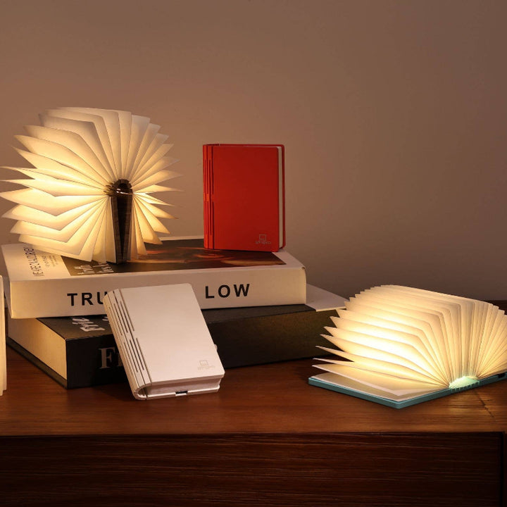 Foldable book-shaped lamps on a wooden surface with a neutral background