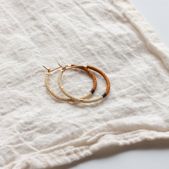 Two hoop earrings on a textured white fabric background