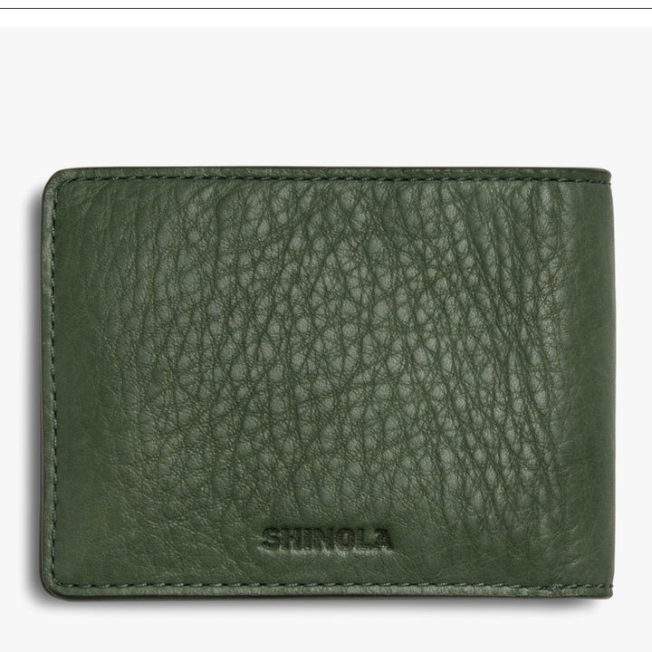Green leather wallet with 'Shinola' branding on a white background