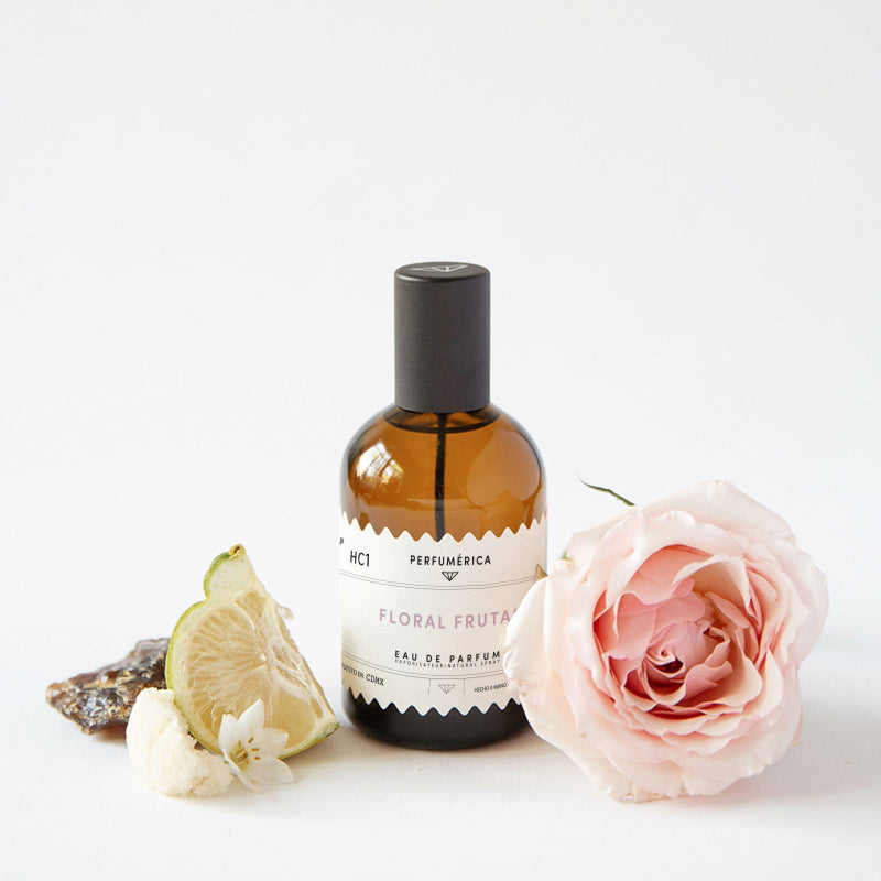 Perfume bottle labeled 'Floral Fruta' with a pink rose and lemon wedge on a white background