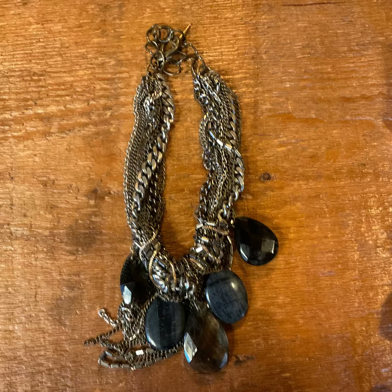 Pair of silver chain earrings with black stones on a wooden surface