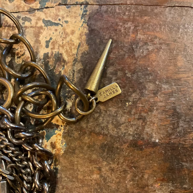 Brass keychain with 'Camilla James' tag on a wooden surface