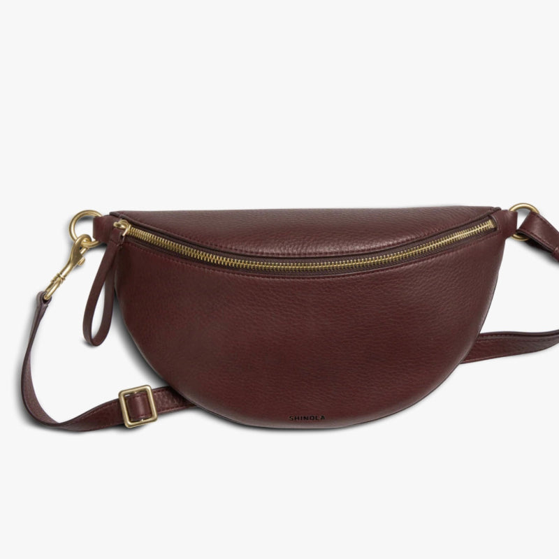 Brown leather waist bag with gold zipper on a white background