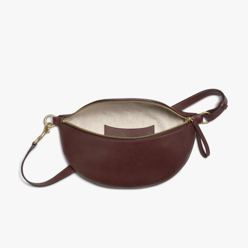 Brown leather bag with a strap on a white background